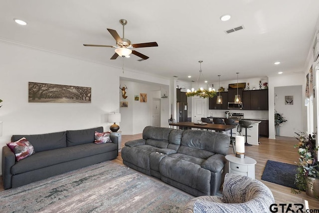 living area featuring recessed lighting, visible vents, light wood-style flooring, and ceiling fan with notable chandelier