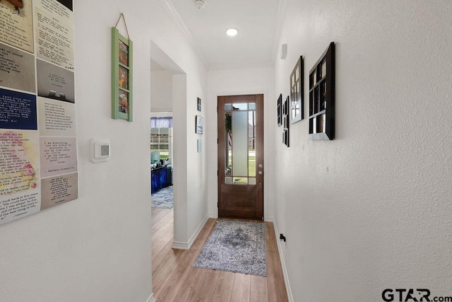 entryway with crown molding, light wood finished floors, and baseboards