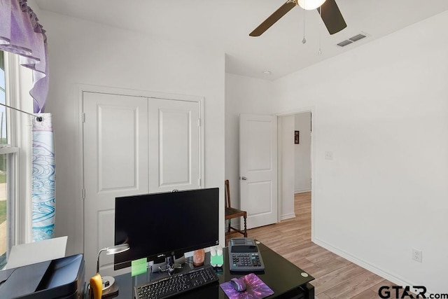 home office featuring visible vents, a healthy amount of sunlight, baseboards, light wood-type flooring, and a ceiling fan