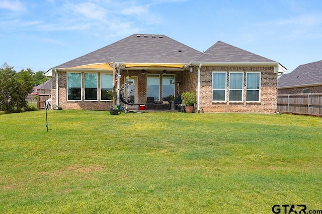 rear view of property with brick siding, fence, and a lawn