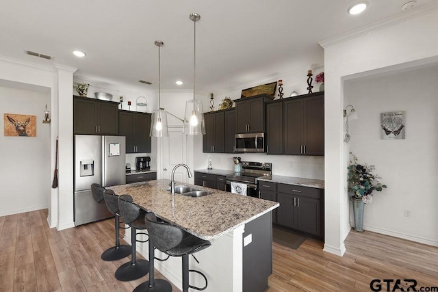 kitchen featuring a sink, a breakfast bar area, visible vents, light stone counters, and appliances with stainless steel finishes