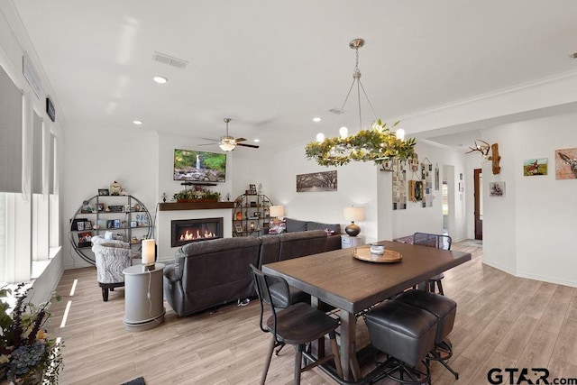 dining room with ceiling fan, visible vents, light wood-style floors, a glass covered fireplace, and recessed lighting