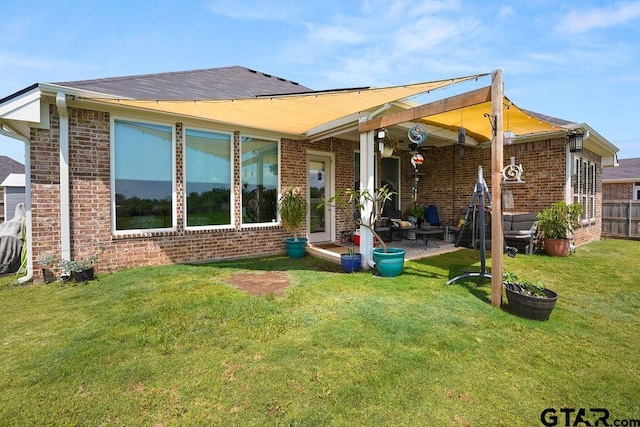 rear view of house with a lawn, fence, a patio area, and brick siding