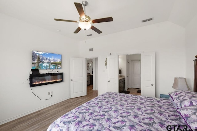 bedroom with visible vents, wood finished floors, and a glass covered fireplace