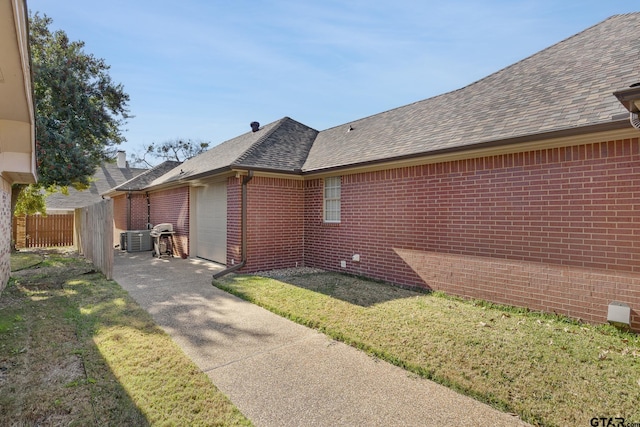 view of property exterior with a garage, cooling unit, and a lawn