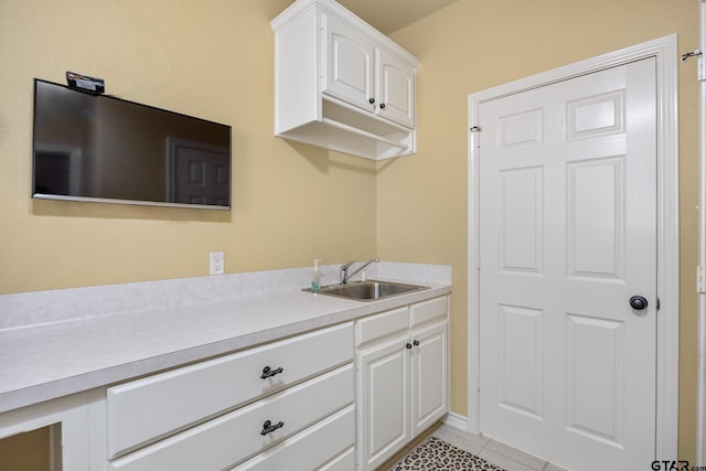 kitchen with white cabinets, light tile patterned floors, and sink