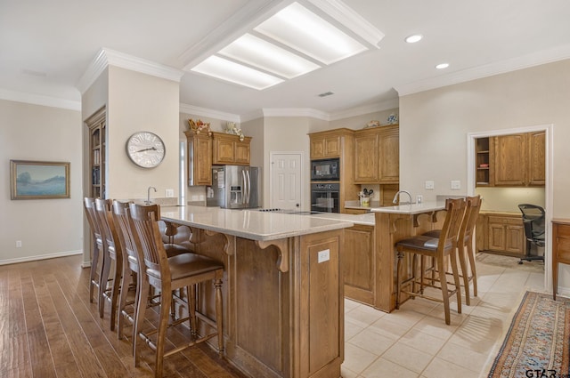 kitchen with kitchen peninsula, a breakfast bar, crown molding, and black appliances