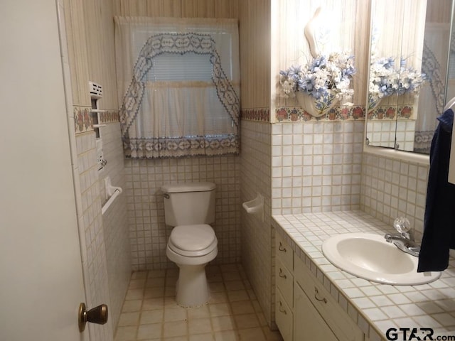 bathroom with tile patterned flooring, vanity, toilet, and tile walls