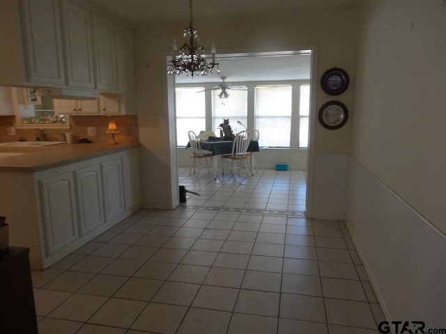 kitchen with pendant lighting, white cabinets, ceiling fan with notable chandelier, sink, and light tile patterned floors