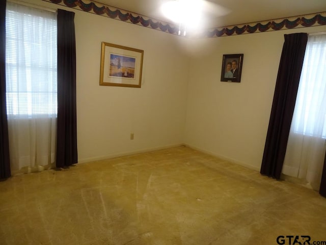 spare room with ceiling fan and light colored carpet