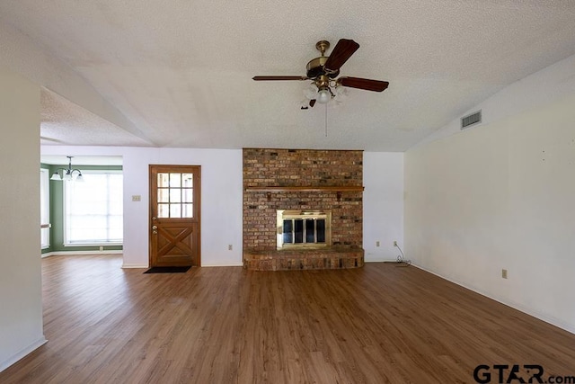 unfurnished living room with wood finished floors, ceiling fan with notable chandelier, visible vents, a textured ceiling, and lofted ceiling