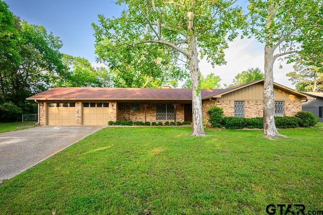 single story home featuring a front lawn, aphalt driveway, brick siding, and a garage