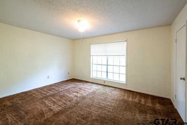 carpeted spare room featuring a textured ceiling and baseboards