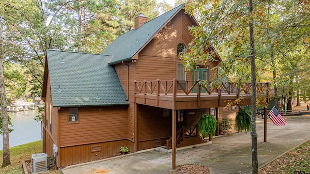 rear view of house with a deck with water view, central air condition unit, and a patio area