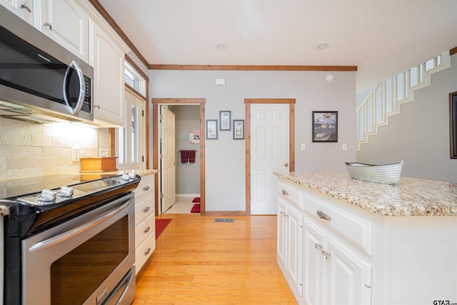 kitchen featuring light hardwood / wood-style flooring, tasteful backsplash, ornamental molding, white cabinetry, and appliances with stainless steel finishes