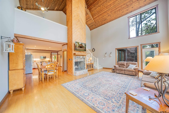 living room with a fireplace, wood ceiling, light hardwood / wood-style flooring, and high vaulted ceiling