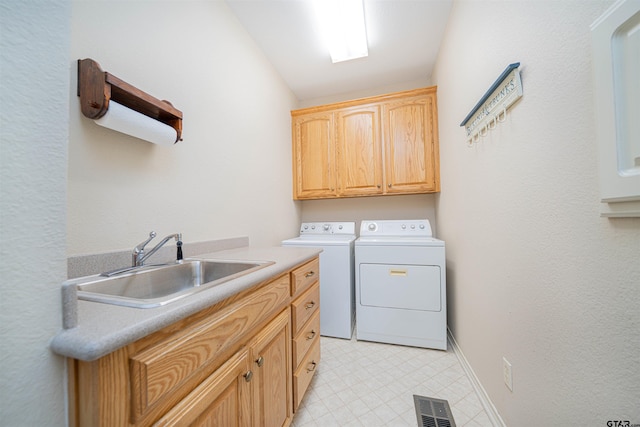 laundry room featuring washing machine and clothes dryer, cabinets, and sink