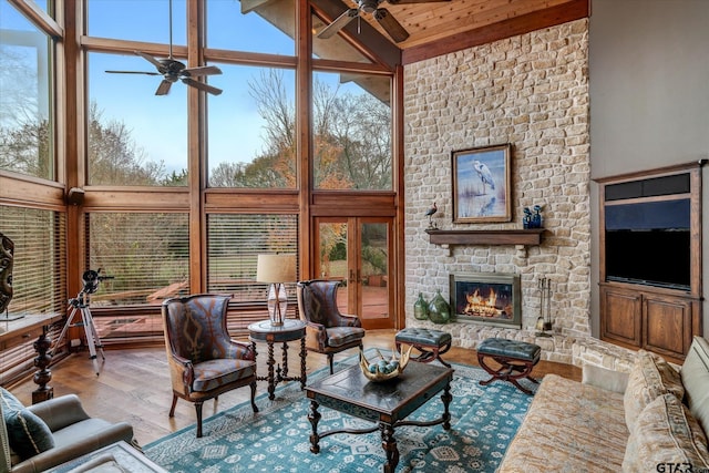 living room featuring high vaulted ceiling, a healthy amount of sunlight, light wood-type flooring, and a fireplace