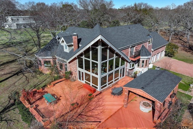 back of house with a balcony, a sunroom, and a fire pit