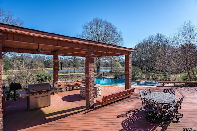 wooden terrace with ceiling fan, a pool with hot tub, and a water view