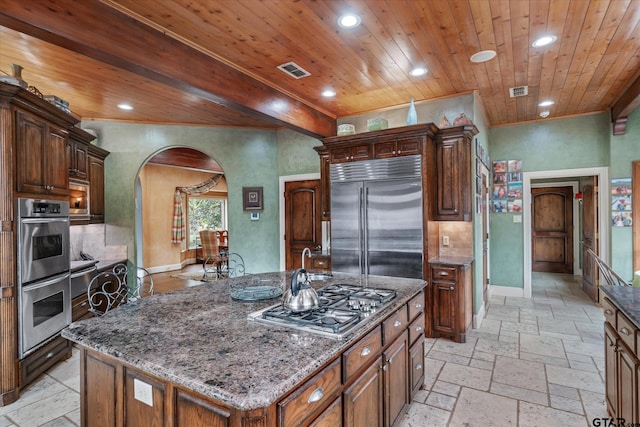 kitchen featuring dark stone counters, wooden ceiling, a kitchen island with sink, and stainless steel appliances