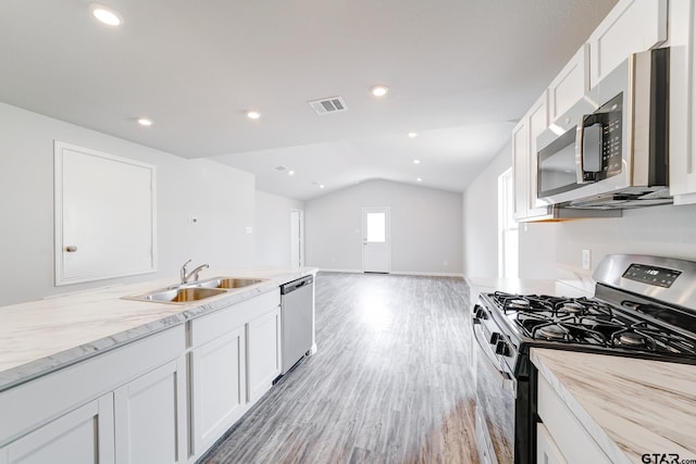 205 Highland Forest Dr, Gilmer, TX 75644 - kitchen with appliances with stainless steel finishes, a sink, lofted ceiling, white cabinetry, and light wood-type flooring