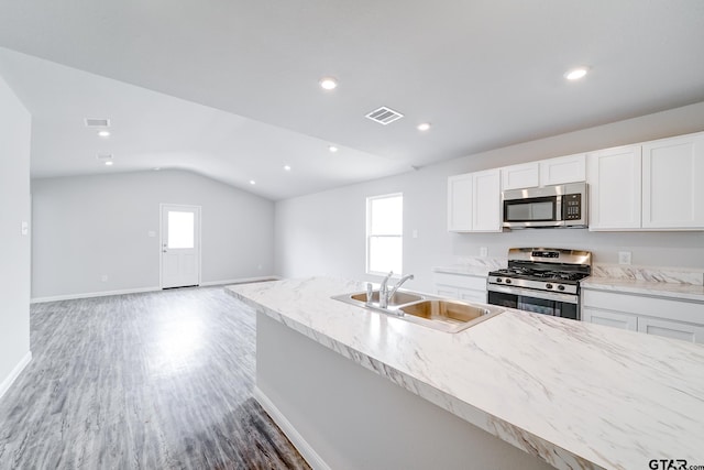 205 Highland Forest Dr, Gilmer, TX 75644 - kitchen with appliances with stainless steel finishes, a sink, vaulted ceiling, white cabinetry, and light wood-type flooring