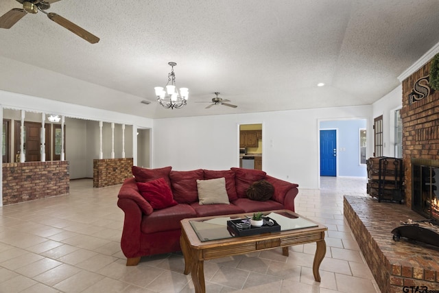 tiled living room featuring ceiling fan with notable chandelier, a textured ceiling, and a fireplace