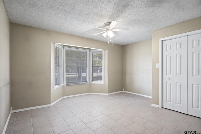 unfurnished bedroom with a textured ceiling, a closet, light tile patterned flooring, and ceiling fan