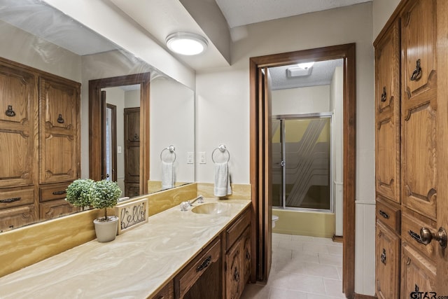 full bathroom featuring tile patterned flooring, toilet, a textured ceiling, combined bath / shower with glass door, and vanity