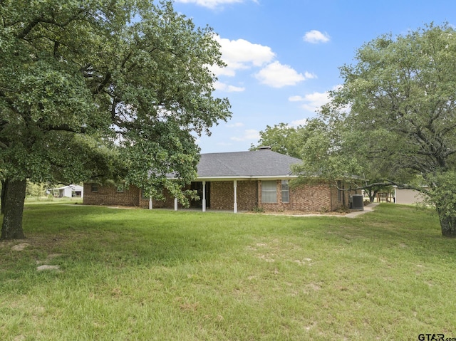 view of front of house with central AC and a front lawn