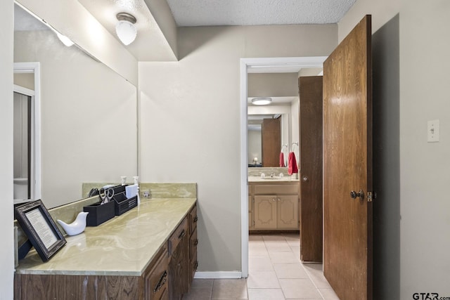 bathroom with tile patterned floors, a textured ceiling, and vanity