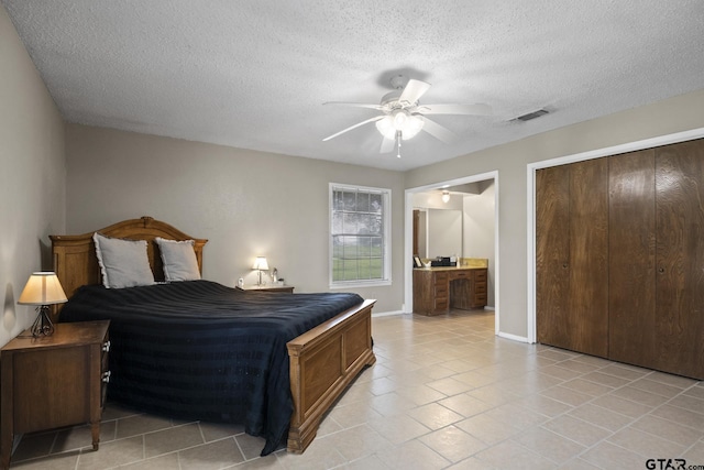 tiled bedroom featuring ceiling fan, a closet, connected bathroom, and a textured ceiling