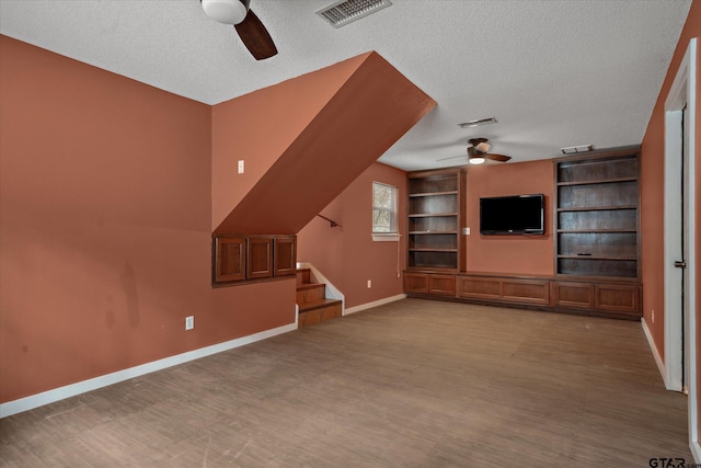 381 Winding Trl, Holly Lake Ranch, TX 75765 - unfurnished living room featuring a ceiling fan, a textured ceiling, stairs, baseboards, and built in features