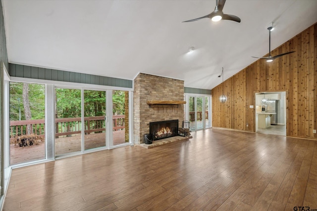 381 Winding Trl, Holly Lake Ranch, TX 75765 - unfurnished living room featuring a ceiling fan, wood walls, a fireplace, wood-type flooring, and high vaulted ceiling
