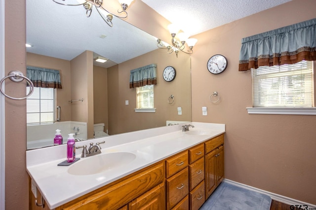 full bath featuring a textured ceiling, double vanity, a sink, and an inviting chandelier