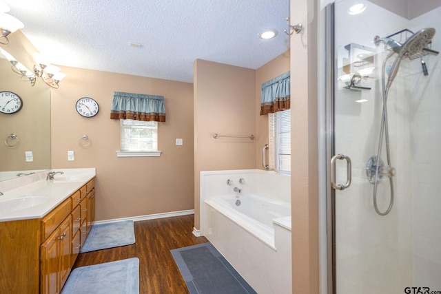 bathroom featuring a textured ceiling, wood finished floors, a sink, a bath, and a stall shower