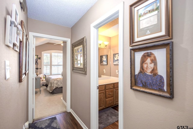 hallway featuring dark wood-type flooring, a textured ceiling, and baseboards