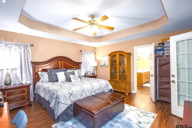 bedroom featuring dark wood-style floors, ceiling fan, refrigerator, a tray ceiling, and a textured ceiling