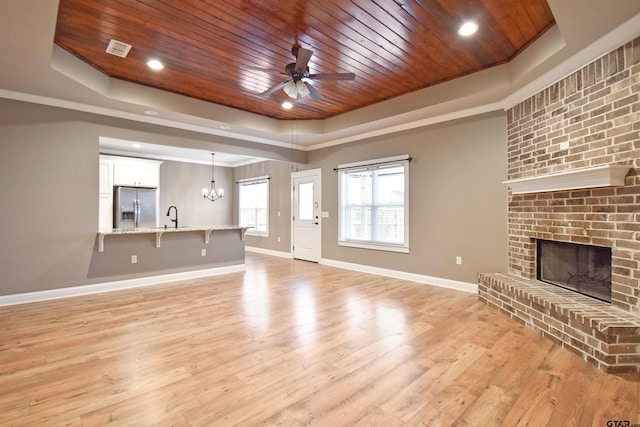 unfurnished living room with a fireplace, sink, a raised ceiling, wooden ceiling, and light wood-type flooring