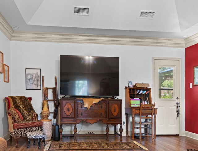 living room featuring hardwood / wood-style floors, ornamental molding, and a tray ceiling