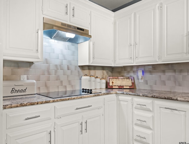 kitchen with dark stone counters, tasteful backsplash, white cabinetry, and black electric stovetop