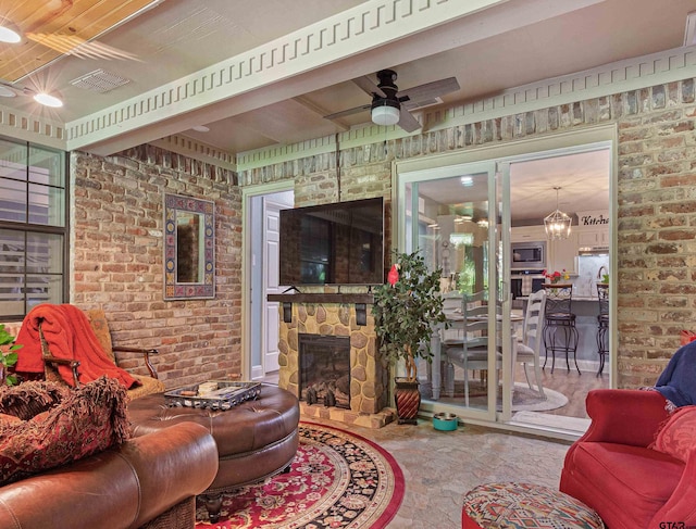 living room featuring a stone fireplace, brick wall, and ceiling fan