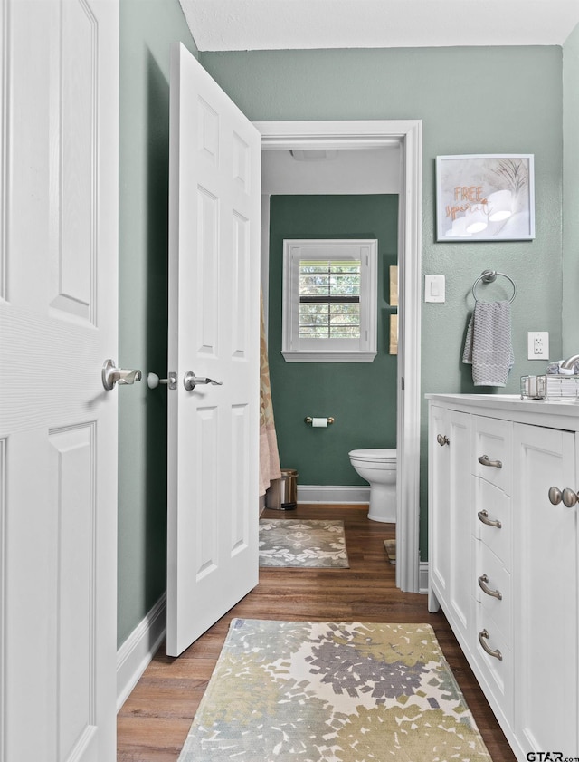 bathroom with hardwood / wood-style floors, vanity, and toilet