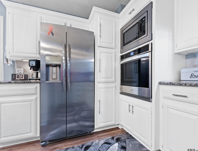 kitchen with dark wood-type flooring, tasteful backsplash, white cabinets, and stainless steel appliances