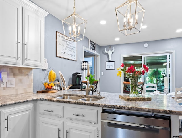 kitchen with backsplash, light stone countertops, hanging light fixtures, sink, and white cabinets