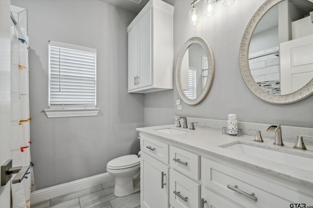 full bathroom with double vanity, toilet, baseboards, and a sink