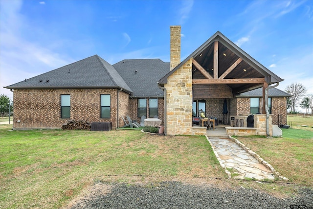 back of property featuring a yard, a patio area, brick siding, and a chimney