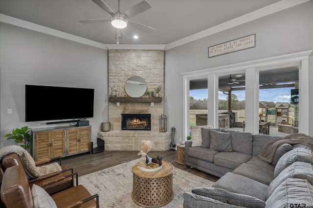 living room with a fireplace, wood finished floors, ceiling fan, and ornamental molding