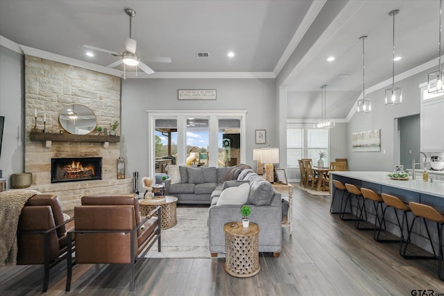 living area with dark wood-style floors, visible vents, a fireplace, ceiling fan, and crown molding